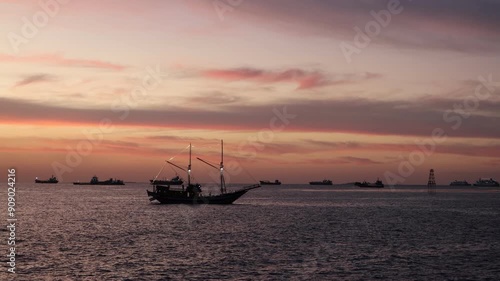 A phinisi boat sails in the afternoon