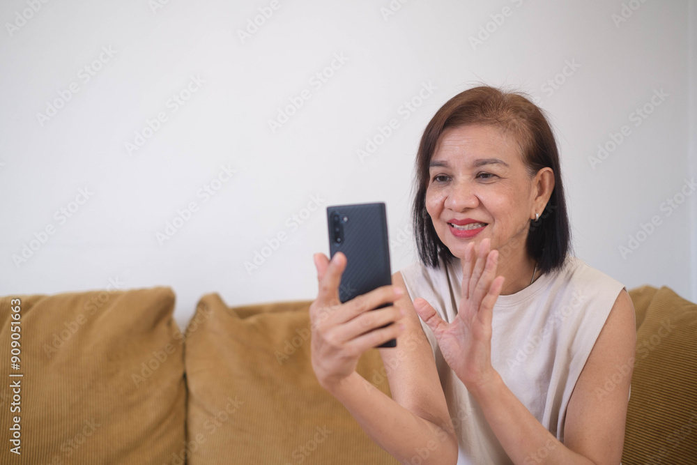 Smiling elderly woman video chatting on smartphone, sitting on a couch. Communication and technology for older adults. Smiling elderly woman video chatting on smartphone, sitting on a couch. Communication and technology for older adults.