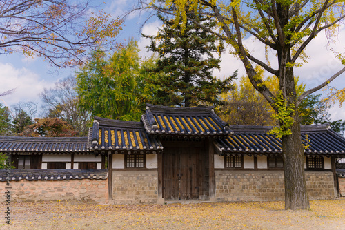 the traditional Korean architecture at Gyeonggijeon Shrine, featuring wooden beams, a tiled roof, and white walls under a clear blue sky. photo