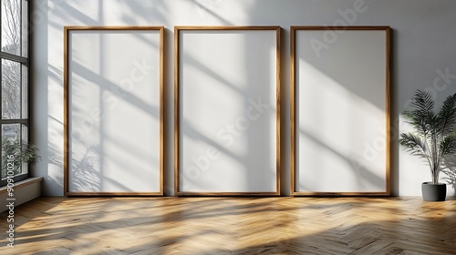 Three vertical white blank wooden framed wall art mockups leaning against the wall in an empty modern room with parquet floor