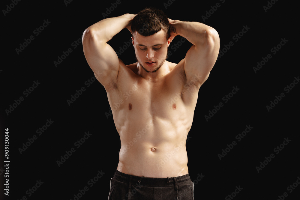 Sexy athletic man with naked torso posing showing his muscles on black background Sexy athletic man with naked torso posing showing his muscles on black background