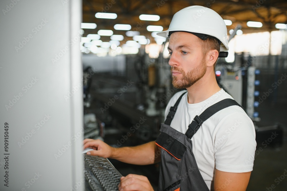 Factory male bearded worker is programming a CNC milling machine with copy space Factory male bearded worker is programming a CNC milling machine with copy space