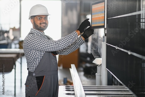 Young Indian male engineer wearing safety workwear standing in the factory