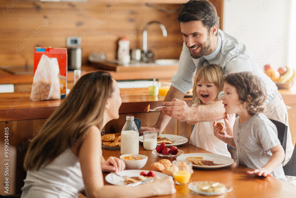 Smiling family enjoying breakfast together in cozy kitchen Smiling family enjoying breakfast together in cozy kitchen