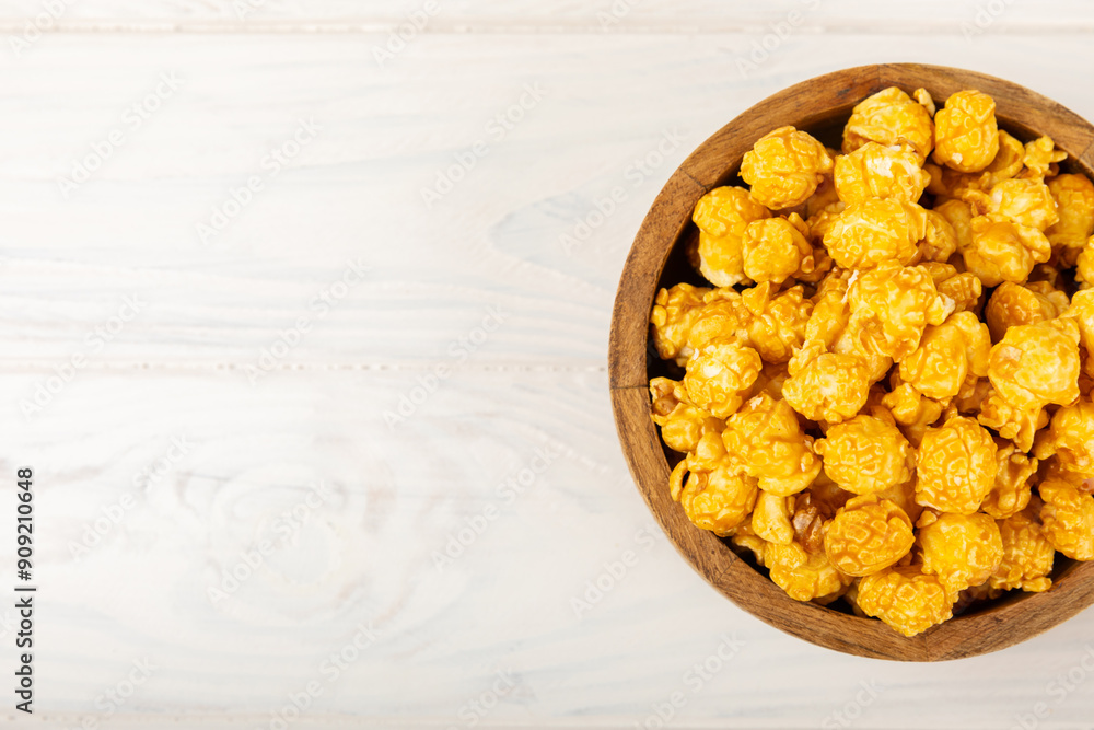 Sweet caramel popcorn in a bowl on a wooden background. Salted caramel popcorn. Caramel sauce. Close up. Topping. Place for text. Copy space Sweet caramel popcorn in a bowl on a wooden background. Salted caramel popcorn. Caramel sauce. Close up. Topping. Place for text. Copy space