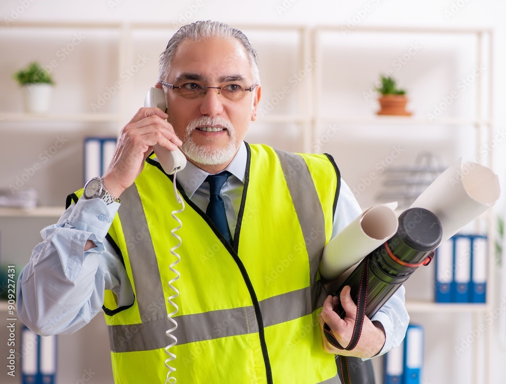 Aged construction engineer working in the office Aged construction engineer working in the office