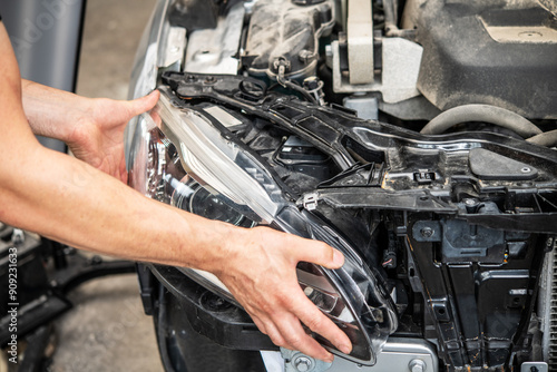 Automotive Maintenance: Skilled Mechanic Replacing Headlight in a Modern Vehicle Engine Compartment