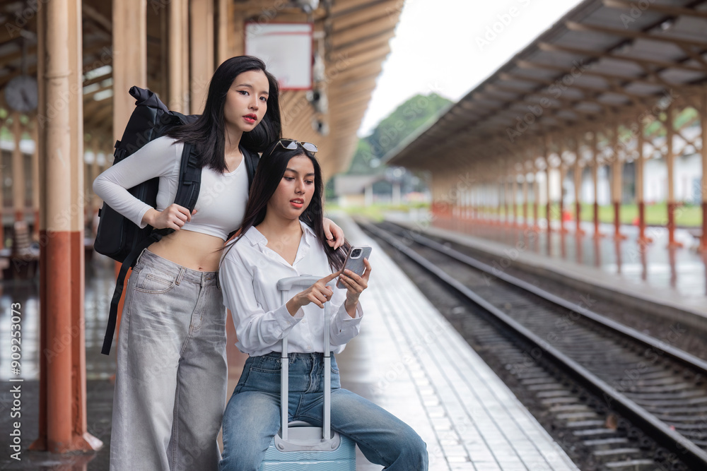 Fototapeta premium Young Lesbian Couple Waiting for Train at Station Modern Travel LGBTQ Love Adventure, Urban Lifestyle Casual Fashion, Public Transport