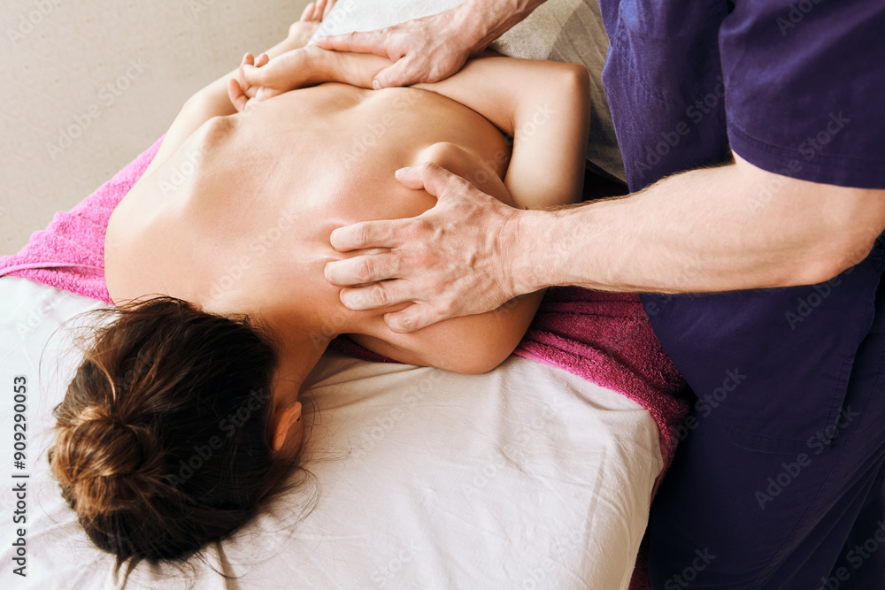 Caucasian woman receives deep tissue massage on her back and neck while lying face down on massage table. Caucasian woman receives deep tissue massage on her back and neck while lying face down on massage table.