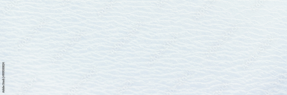 Obraz premium Beautiful winter background with snowy ground. Natural snow texture. Wind sculpted patterns on snow surface. Wide panoramic texture for background and design.