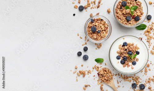 Granola, yogurt, blueberries in bowls on grey background, top view, copy space. Healthy breakfast menu concept. mockup