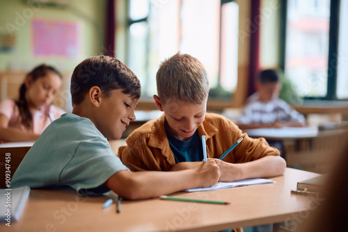 Happy schoolboys learning together in classroom.