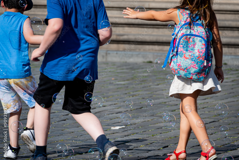 Children play with soap bubbles in a city square. Children play with soap bubbles in a city square.