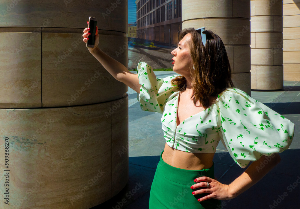 Joyful young caucasian woman winks, bites her tongue, takes selfie on phone. Blonde model wears hat in sunny weather. Positive emotions concept. High quality photo