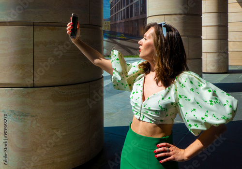 Obraz na płótnie Joyful young caucasian woman winks, bites her tongue, takes selfie on phone. Blonde model wears hat in sunny weather. Positive emotions concept. High quality photo w salonie