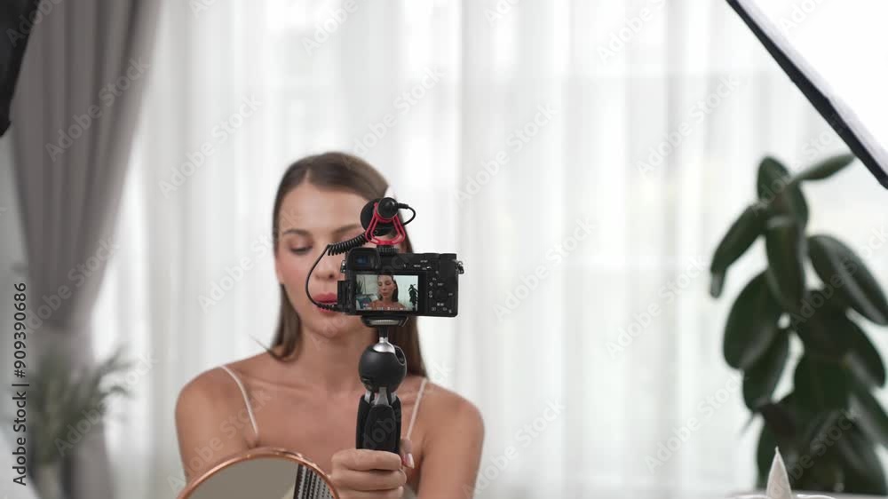 Young woman making beauty and cosmetic tutorial video content for social media. Beauty blogger smiles to camera while showing how to beauty care to audience or followers. Adit Young woman making beauty and cosmetic tutorial video content for social media. Beauty blogger smiles to camera while showing how to beauty care to audience or followers. Adit