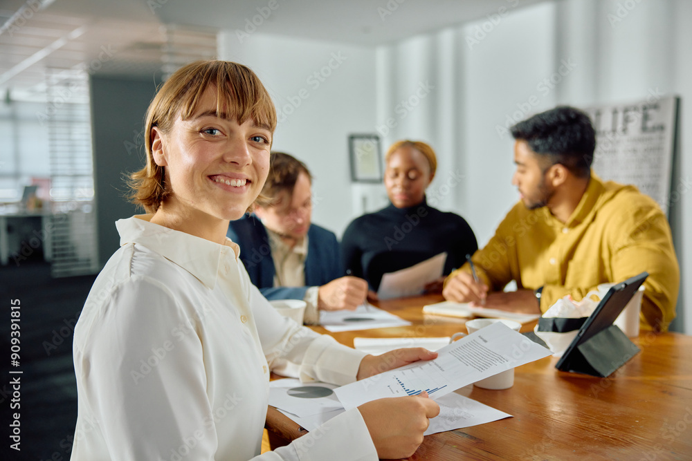 Four young multiracial adults in businesswear meeting at conference table with digital tablet in office Four young multiracial adults in businesswear meeting at conference table with digital tablet in office