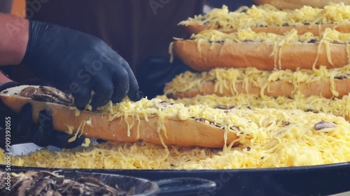 cook preparing cheese and mushroom streetfood baguettes on a festival photo