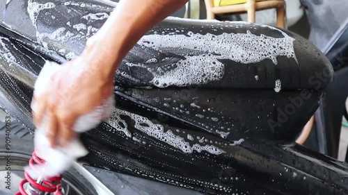 A man washing a motorbike. Mengelap sepeda motor dengan kain berbusa.  photo