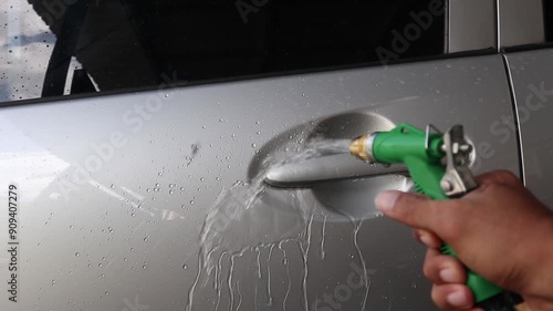 A man is washing a car. Sprayin water to body car.  photo