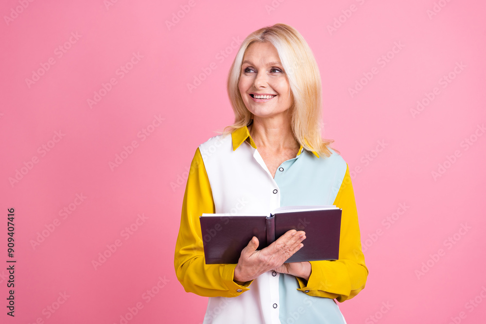 Photo of nice aged lady hold book look empty space wear shirt isolated on pink color background Photo of nice aged lady hold book look empty space wear shirt isolated on pink color background