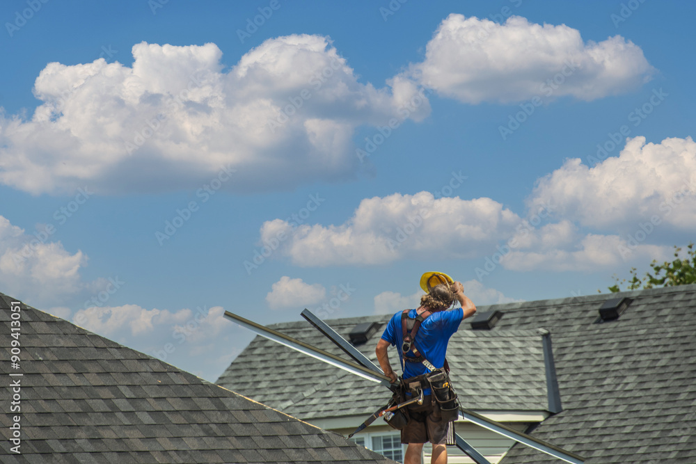 Roofer on the roof covered with bituminous shingles Roofer on the roof covered with bituminous shingles