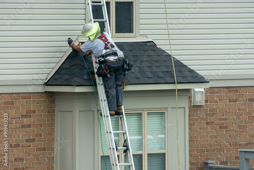 A roofer attaches tiles to the corners of a bay window photo