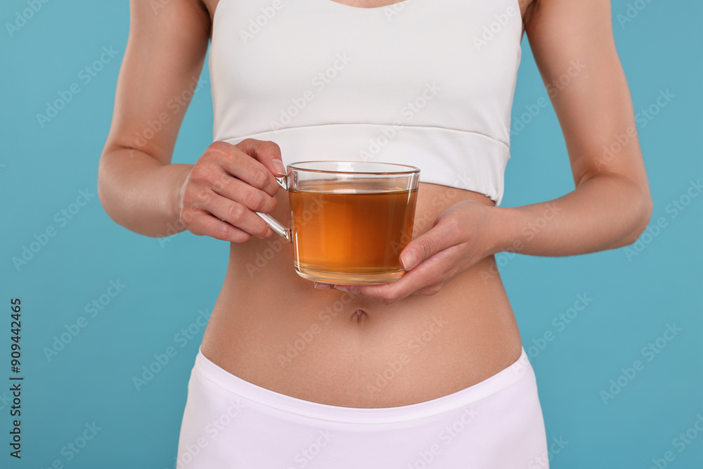 Weight loss concept. Woman with cup of diet tea on light blue background, closeup Weight loss concept. Woman with cup of diet tea on light blue background, closeup