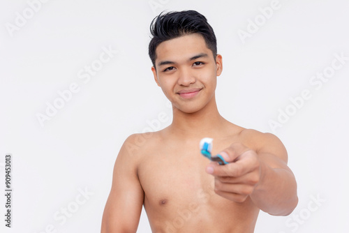 Half naked young asian man handing over a toothbrush with toothpaste, promoting daily proper oral hygiene. Isolated on white background. photo