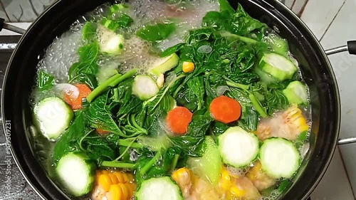 cook sayur bening or clear soup in a pan. contains spinach, corn, carrots and other vegetables. indonesian food