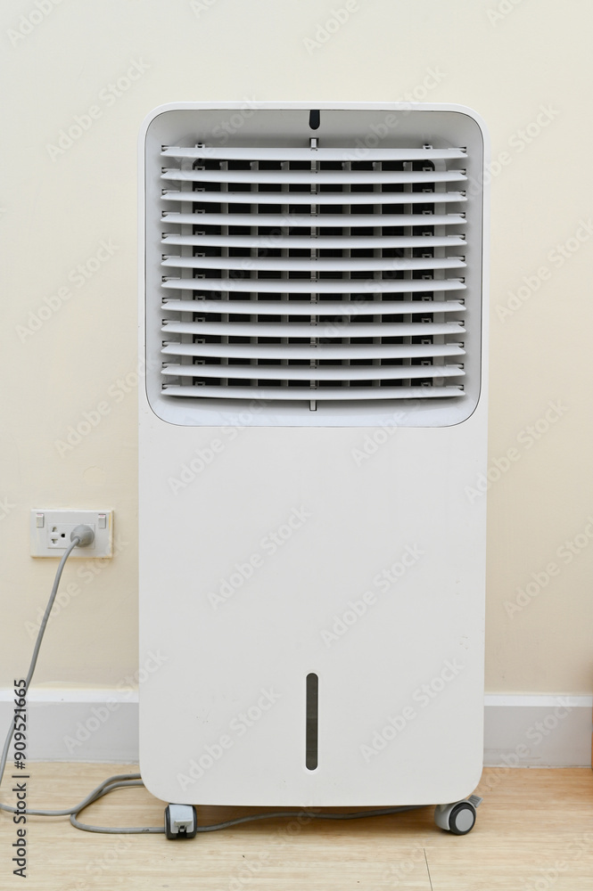 Portable air cooler with white design, plugged in, and ready for use in an indoor setting. Portable air cooler with white design, plugged in, and ready for use in an indoor setting.