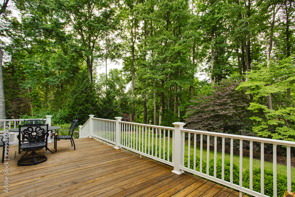 Scenic Wooden Patio With Outdoor Furniture Set Amidst Lush Green Trees Scenic Wooden Patio With Outdoor Furniture Set Amidst Lush Green Trees