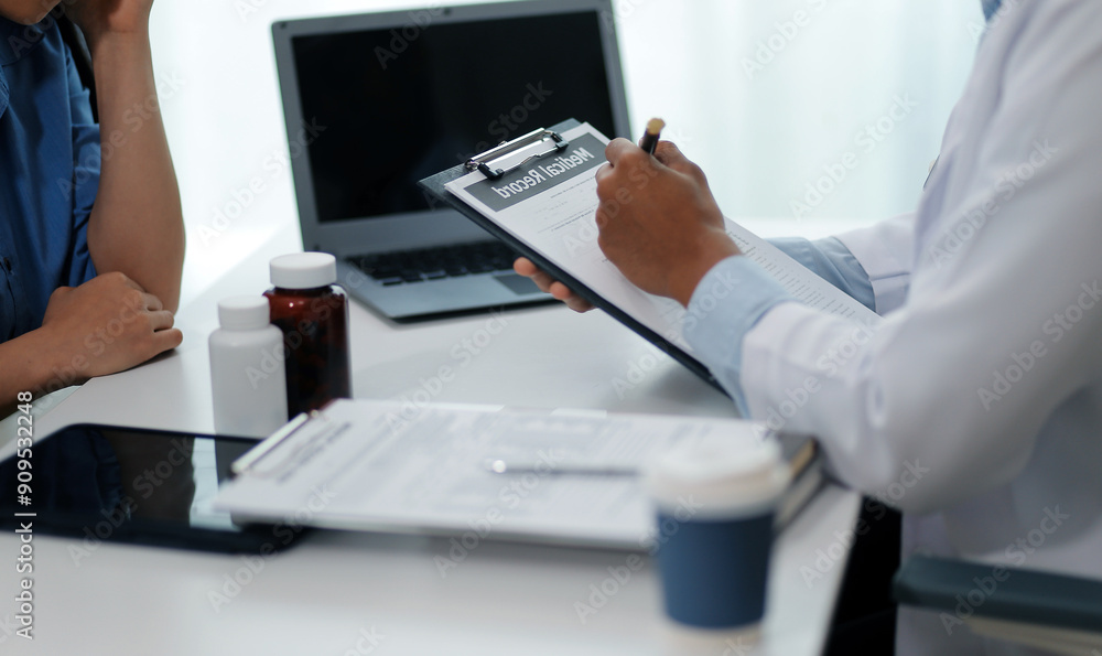 Doctor and patient sitting near each other at the wooden desk in clinic. Female physician's pointing to a records form. Medicine concept Doctor and patient sitting near each other at the wooden desk in clinic. Female physician's pointing to a records form. Medicine concept