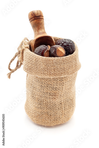 Close-up of Organic Soapnuts or Reetha (Sapindus mukorossi) berries, in a jute bag with a scoop, Isolated on a white background. photo