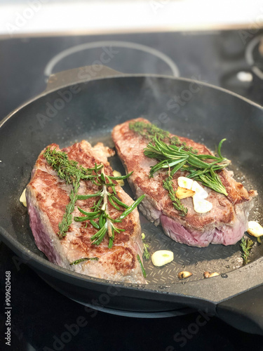 grilled beef steak with rosemary and garlic on a frying pan