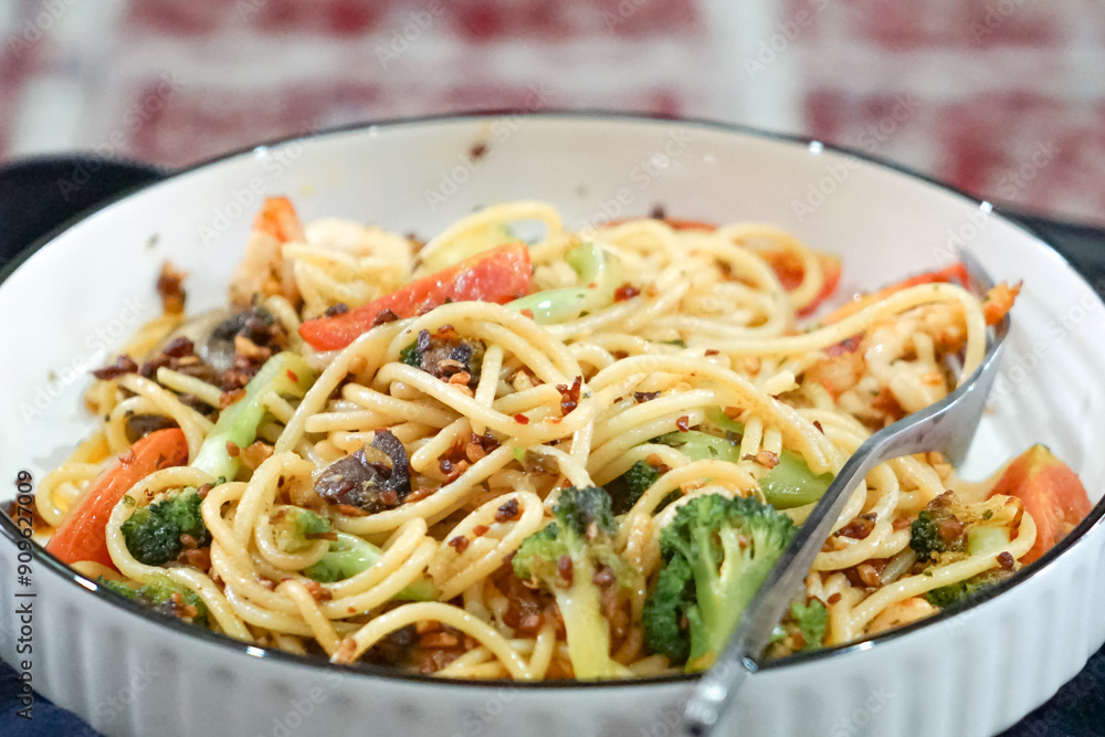 Stir-fried pasta with prawn, broccoli, mushroom and tomato. Served on a white plate. Stir-fried pasta with prawn, broccoli, mushroom and tomato. Served on a white plate.
