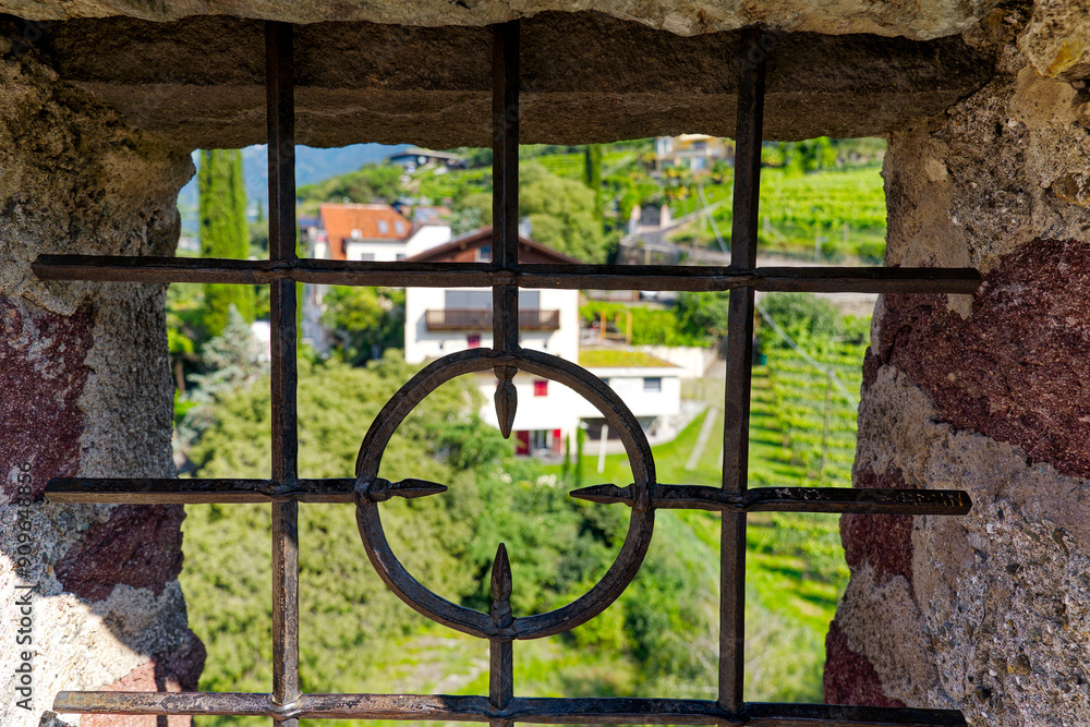 Φωτογραφία Looking through window with metal grid on top of medieval powder tower at Italian City of Meran on a sunny summer day