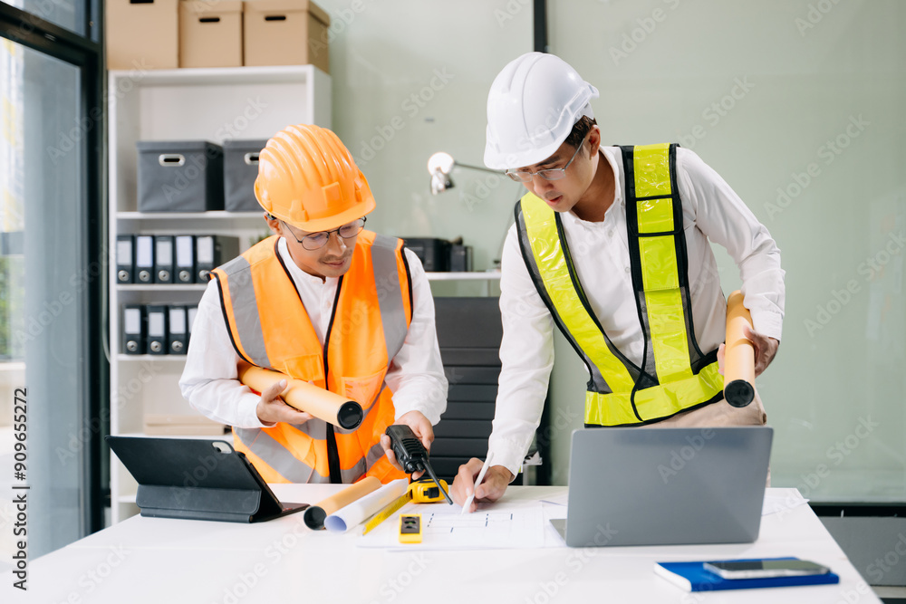Contractor and architect looking at plan, tablet, laptop and talking about working on big project. Contractor and architect looking at plan, tablet, laptop and talking about working on big project.