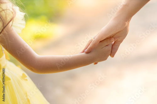 parent holding child's hand, happy mother and daughter holding hands outdoors in summer, mothers Day