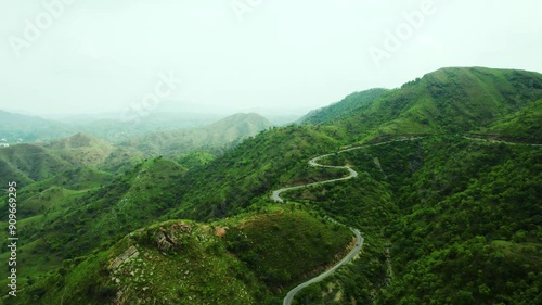 4K shot of vehicles passing on scenic road in mountains and clouds in sky at Rayta in Udaipur, Rajasthan, India. Monsoon clouds and green hills of Rayta. Tourism and holidays background. photo