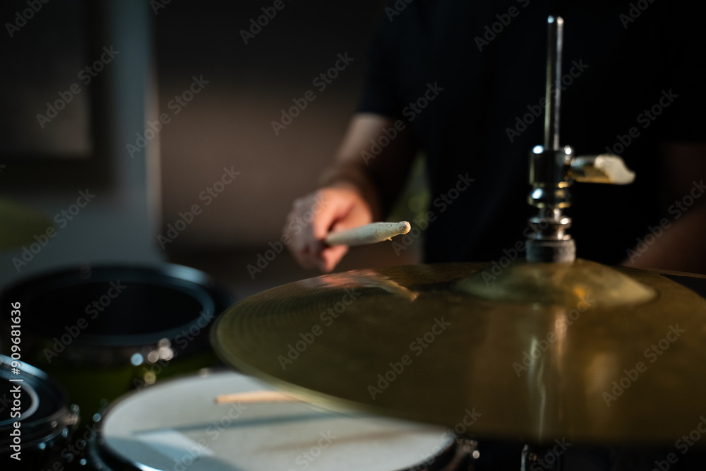 The drummer hits the hi-hat with a drumstick, making a loud, sonorous sound. The drummer is wearing a black shirt, and the cymbal is large and golden. The camera is aimed at the plate in close-up The drummer hits the hi-hat with a drumstick, making a loud, sonorous sound. The drummer is wearing a black shirt, and the cymbal is large and golden. The camera is aimed at the plate in close-up