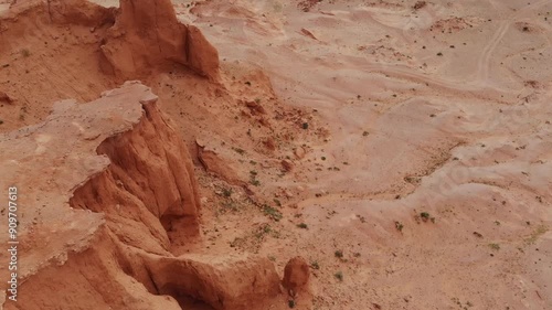The Flaming Cliffs in the Gobi Desert, Mongolia, under a clear blue sky, showcasing its iconic red sandstone formations and barren landscape.