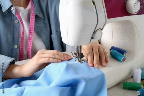 Seamstress working with sewing machine at table indoors, closeup