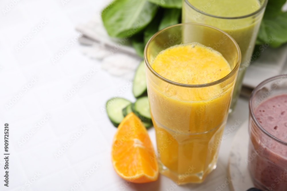 Tasty smoothies in glasses and ingredients on white tiled table, closeup. Space for text Tasty smoothies in glasses and ingredients on white tiled table, closeup. Space for text