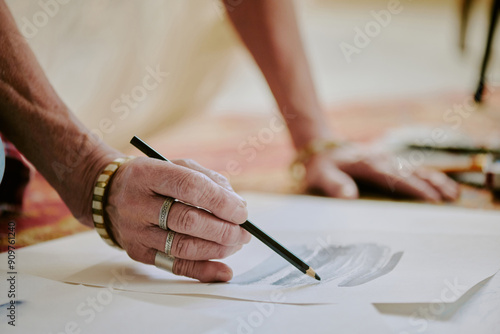 Closeup of wrinkled hand of unrecognizable senior female artist drawing pencil sketch, copy space photo