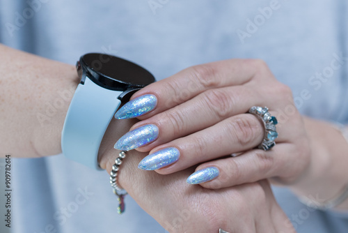 Female hand with long nails and bright light blue and silver manicure	 photo