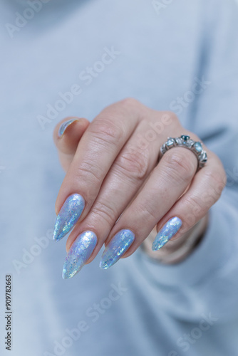 Female hand with long nails and bright light blue and silver manicure	 photo