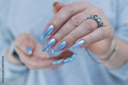 Female hand with long nails and bright light blue and silver manicure 