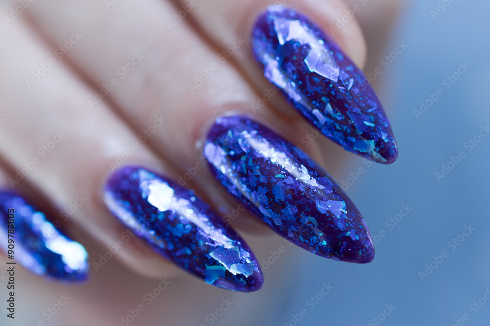 Female hand with long nails and a blue and purple color nail polish Female hand with long nails and a blue and purple color nail polish
