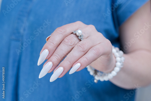 Woman's hands with long nails and a light white color nail polish